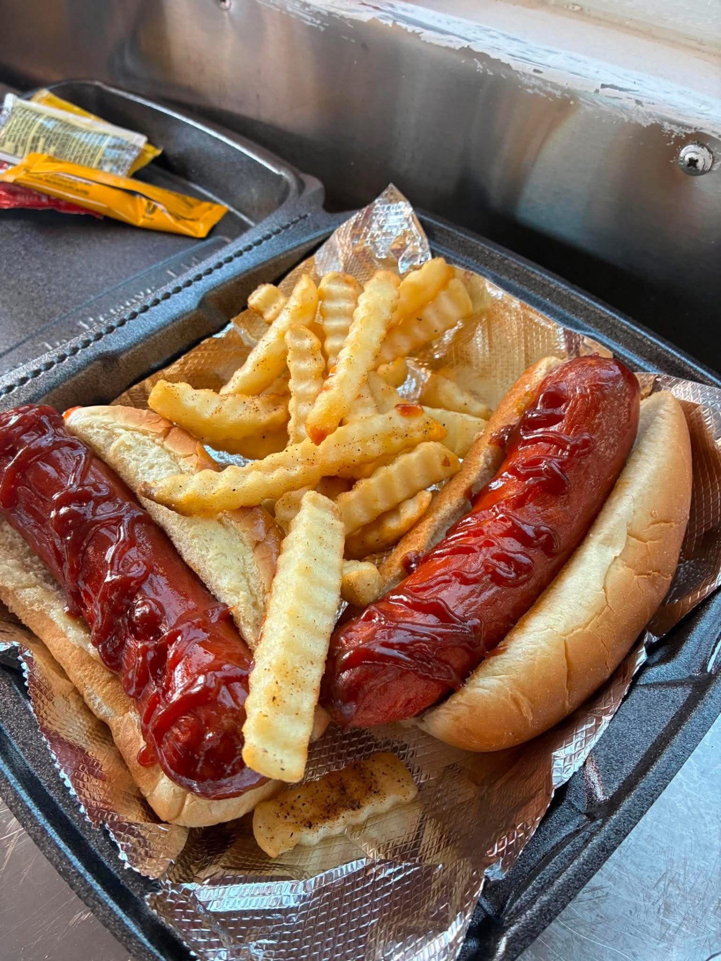 Two saucy hot links on buns with seasoned crinkle fries