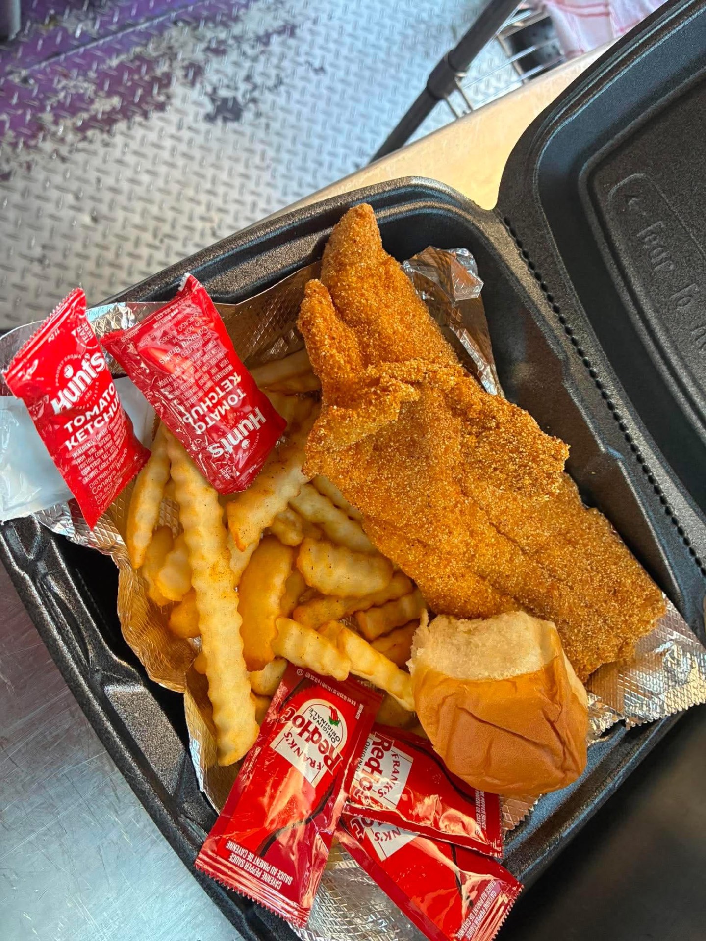 Golden cornmeal-fried catfish with fries and a roll
